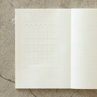 Open notebook with grid paper on a textured concrete surface